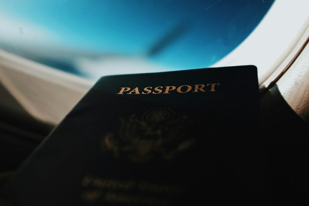 Passport held up by an airplane window before an international trip